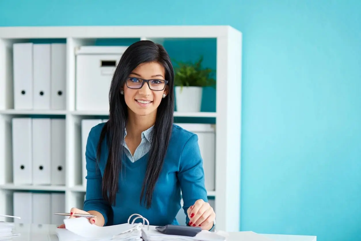 A woman sitting at her desk with a calculator.