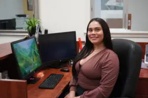 A woman sitting at her desk in front of two computers.