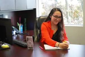 A woman sitting at her desk with a phone and a notebook.