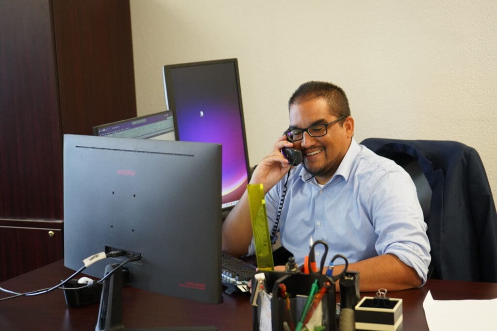 A man sitting at his desk on the phone.