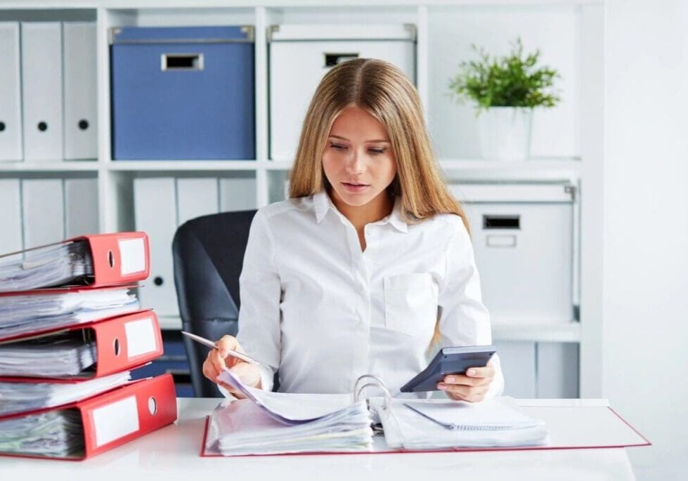 A woman sitting at her desk with papers and cell phones.